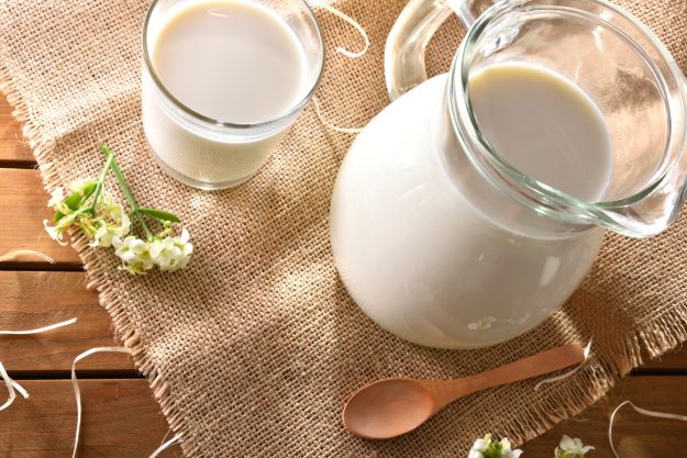 Glass and jug with milk on wooden table outdoor top