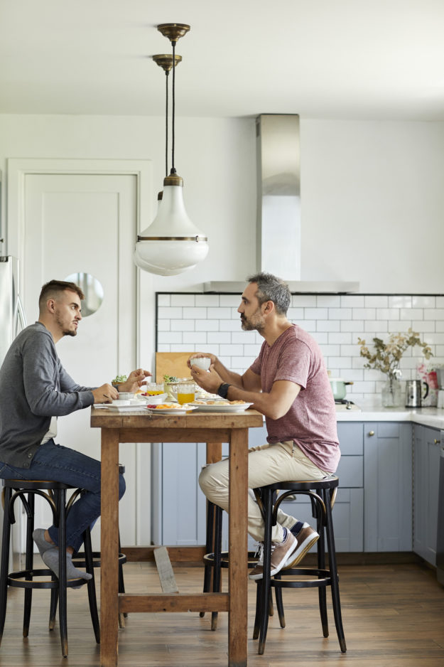 Gay couple talking while eating breakfast at home